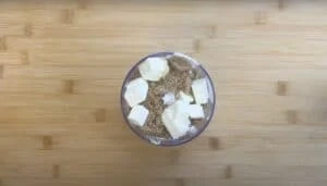Butter and brown sugar cubes in a glass container on a wooden surface, ready for baking preparation.